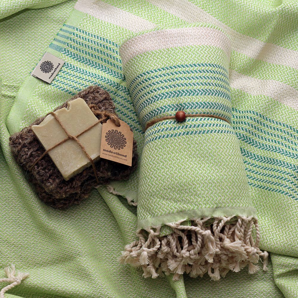 Tricolor Turkish towel with various shades of green. There is a wool mitt for body washing and a tan green soap tied to the top of the mitt.